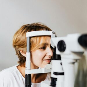 A woman undergoing an eye test using medical equipment, symbolizing what eye care means and why it is important for healthy vision