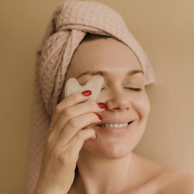 Woman using a jade stone on her under-eye area showing how to prevent puffy eyes naturally | clickshopfy.in